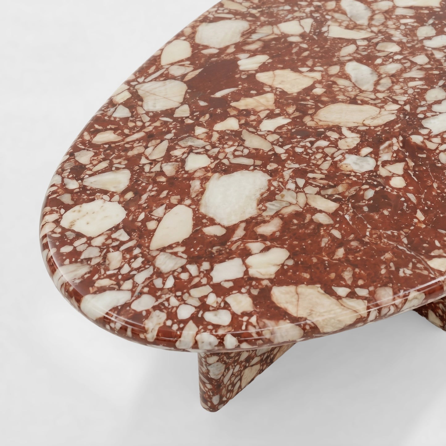 Side profile of a luxury Red Bulgari marble coffee table featuring a sculptural two-pedestal base and a thick pebble-shaped top against a minimalist white background.