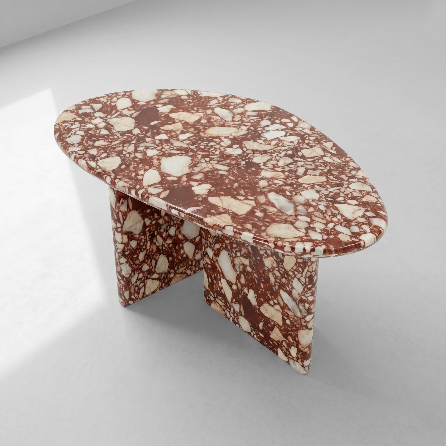 High-angle top view of a pebble-shaped coffee table crafted from Red Bulgari stone, emphasizing its unique organic silhouette and bold natural stone patterns.