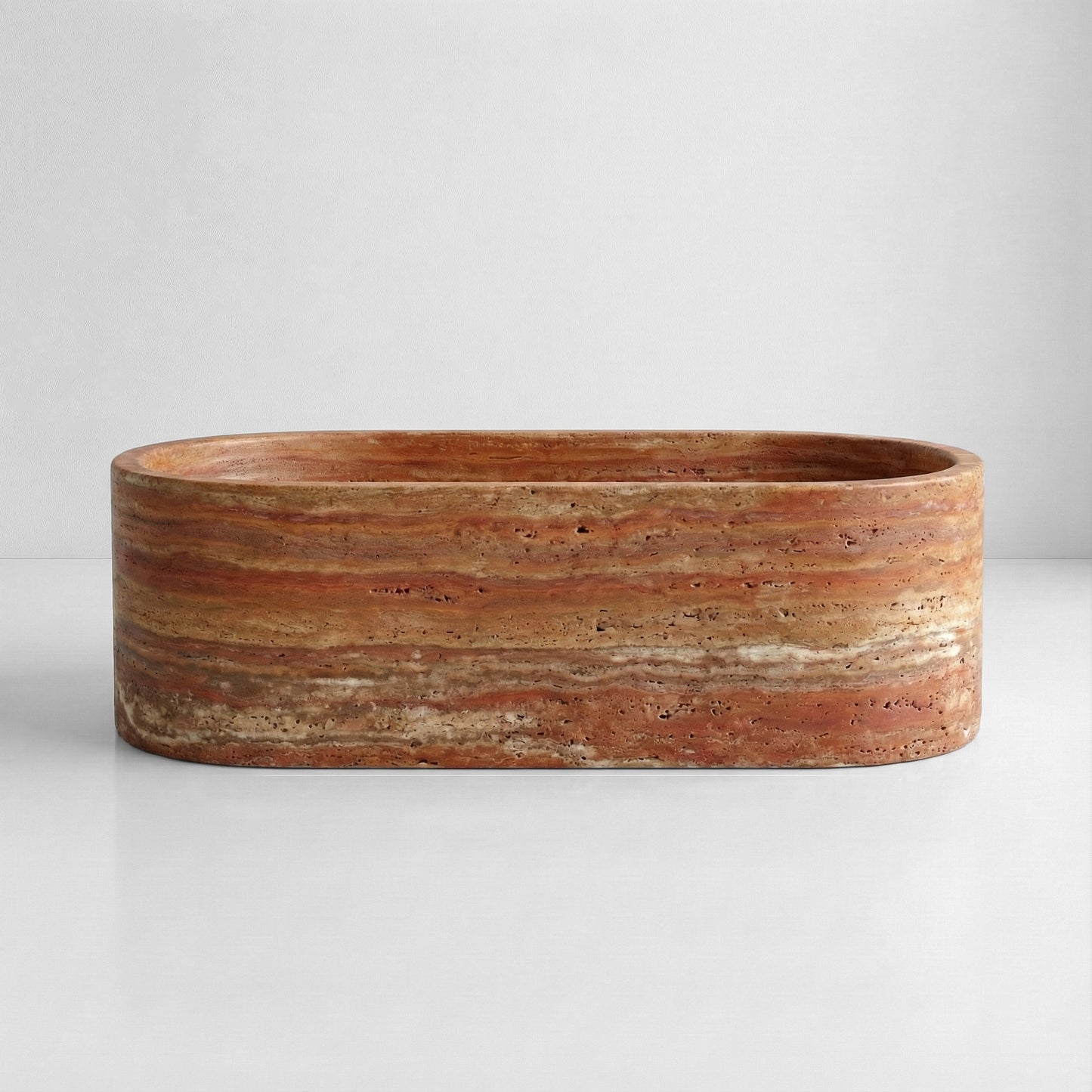 Front elevation of a freestanding Red Travertine bathtub showcasing distinct horizontal rust and ochre sedimentary layers.