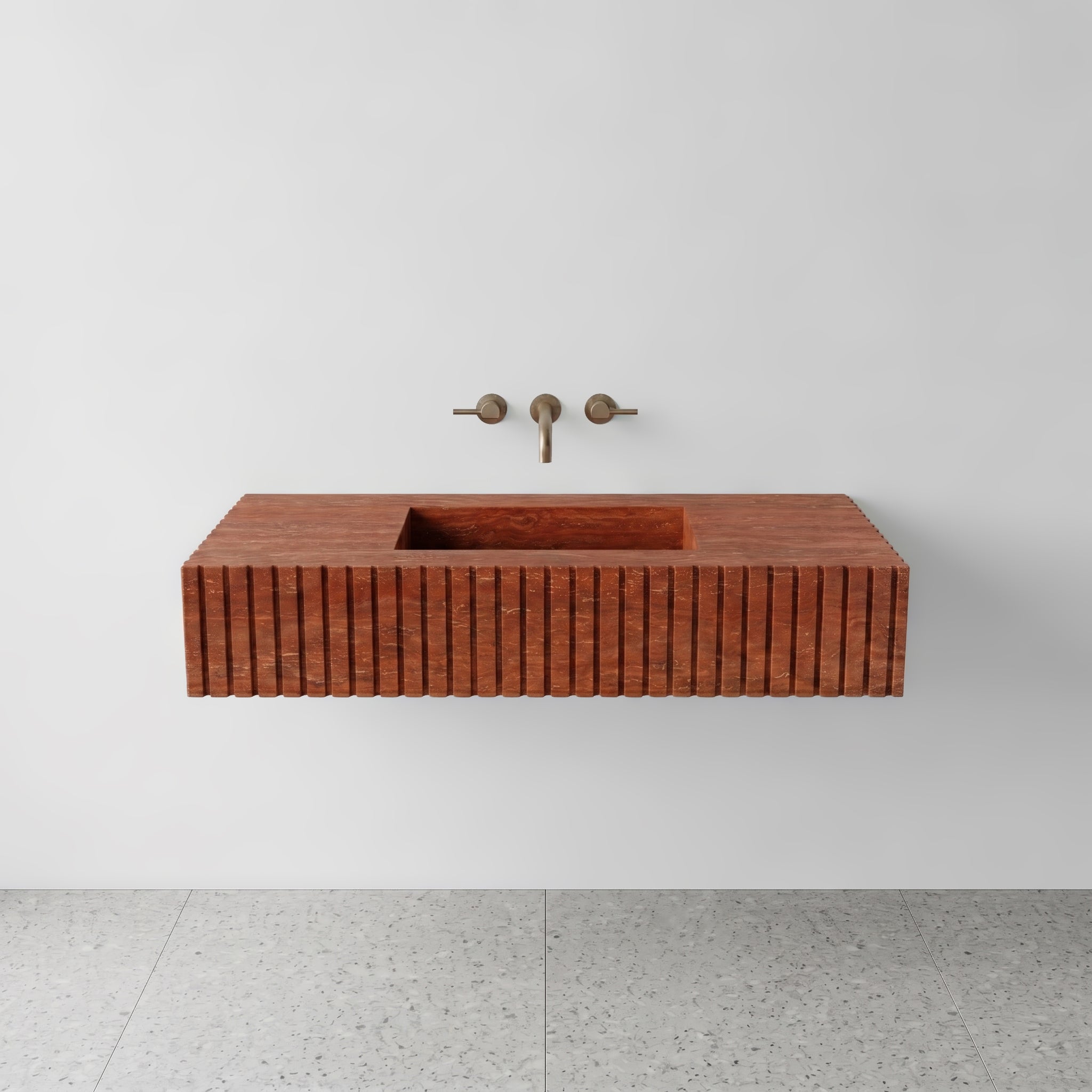 Front studio view of a luxury floating double vanity sink made of rich Red Travertine stone, featuring a bold fluted apron front design and wall-mounted brushed bronze faucets.