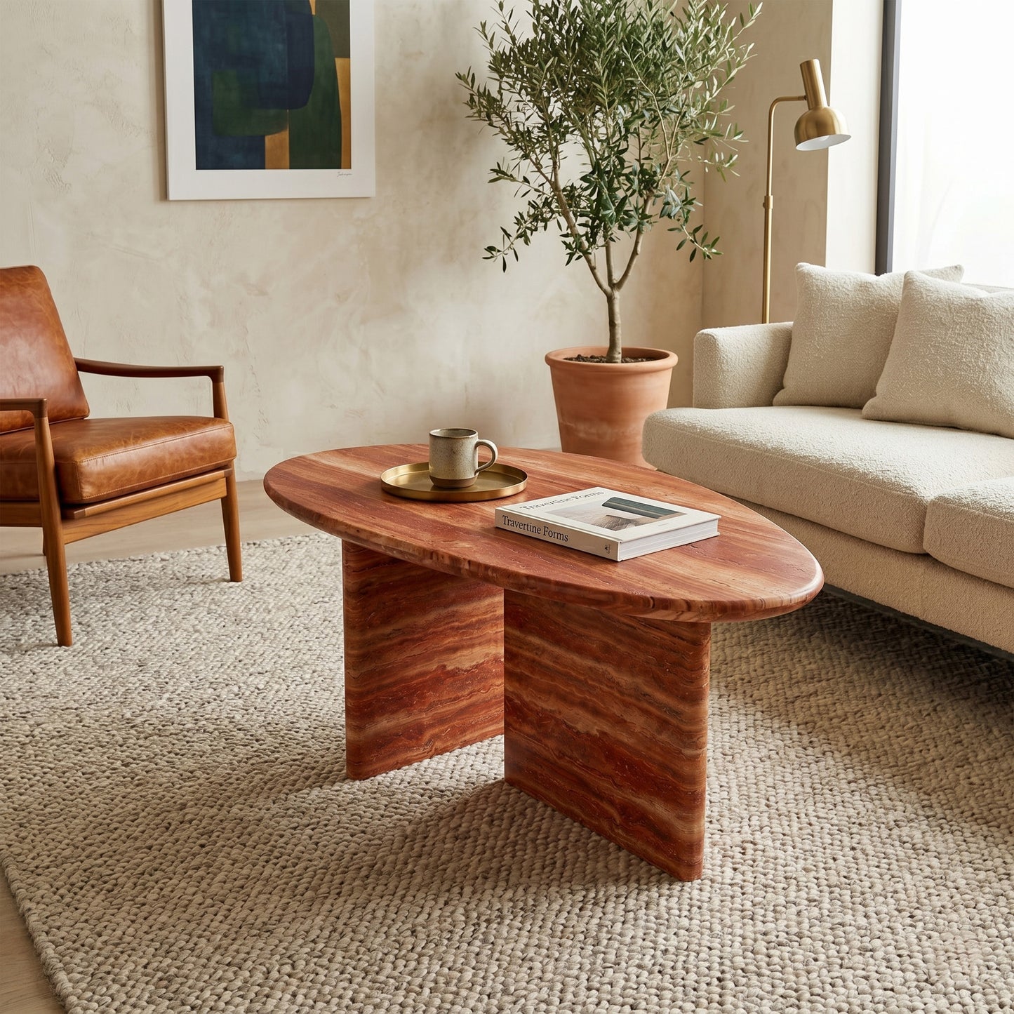 Contemporary living room interior featuring an organic pebble-shaped red travertine coffee table as a centerpiece, styled with decor on a neutral textured rug alongside a cream sofa.