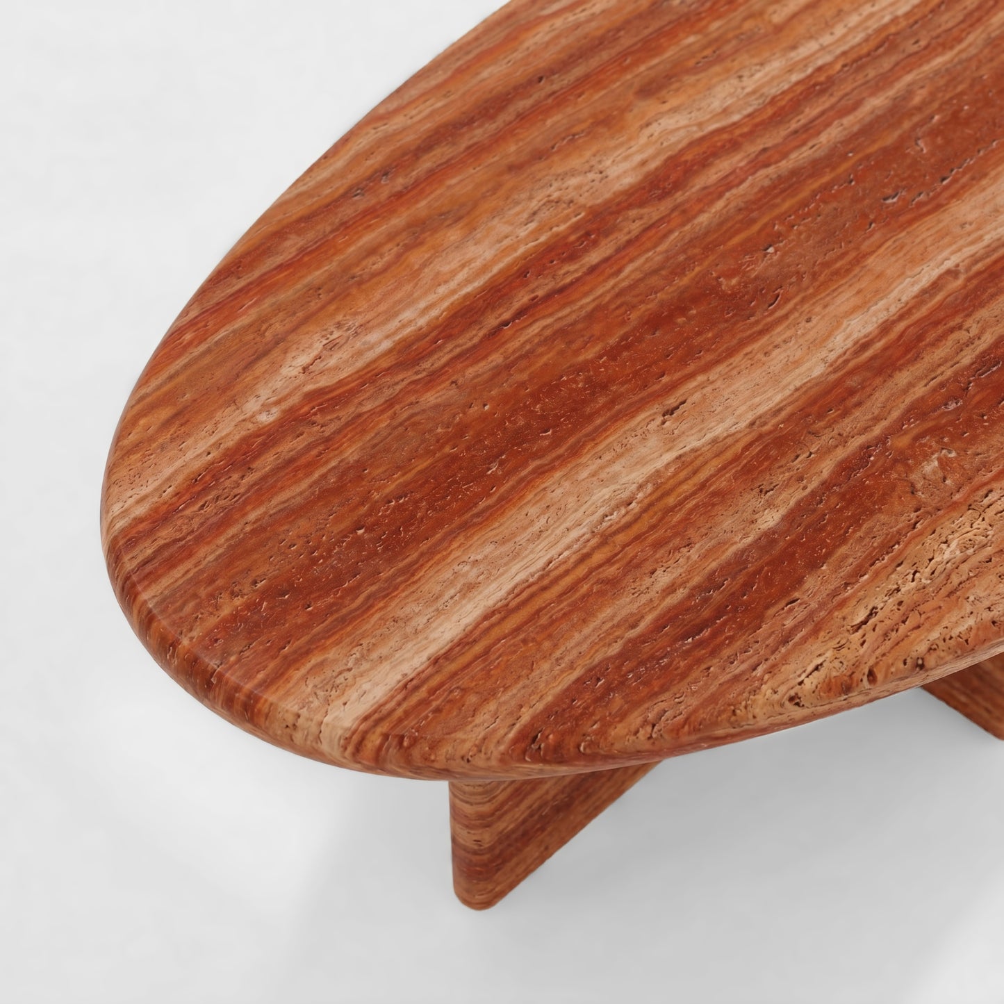 Side profile of a luxury red travertine coffee table featuring a sculptural pedestal base and a thick pebble-shaped top against a minimalist white background.