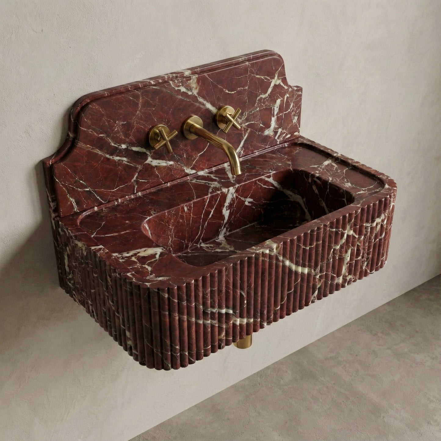 High-angle side view of a vintage-style Rosso Levanto marble sink, featuring an integrated stone backsplash, wall-mounted brass faucet, and fluted apron.