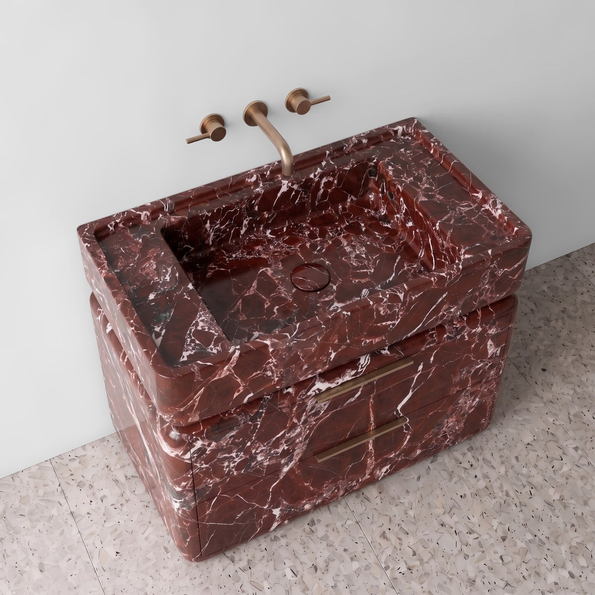 High-angle perspective view of the Rosso Levanto marble double-drawer vanity, highlighting the integrated trough sink with a matching stone drain cover, raised perimeter border, rounded drawer contours, brushed brass linear hardware, and deep wine-red stone with white calcite spiderweb veining.