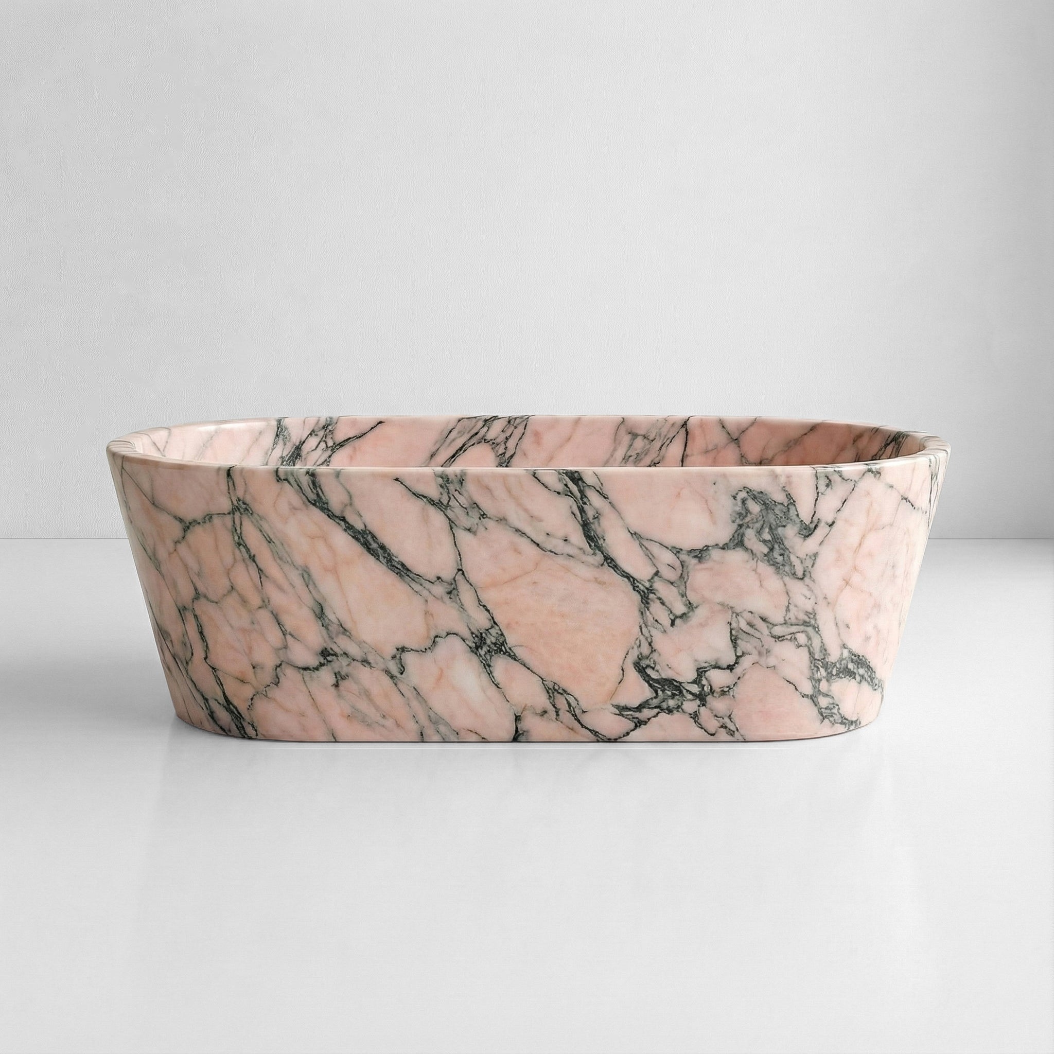 Front profile of a freestanding Rosso Portogallo marble bathtub featuring soft pink natural stone with dramatic charcoal and grey veining.