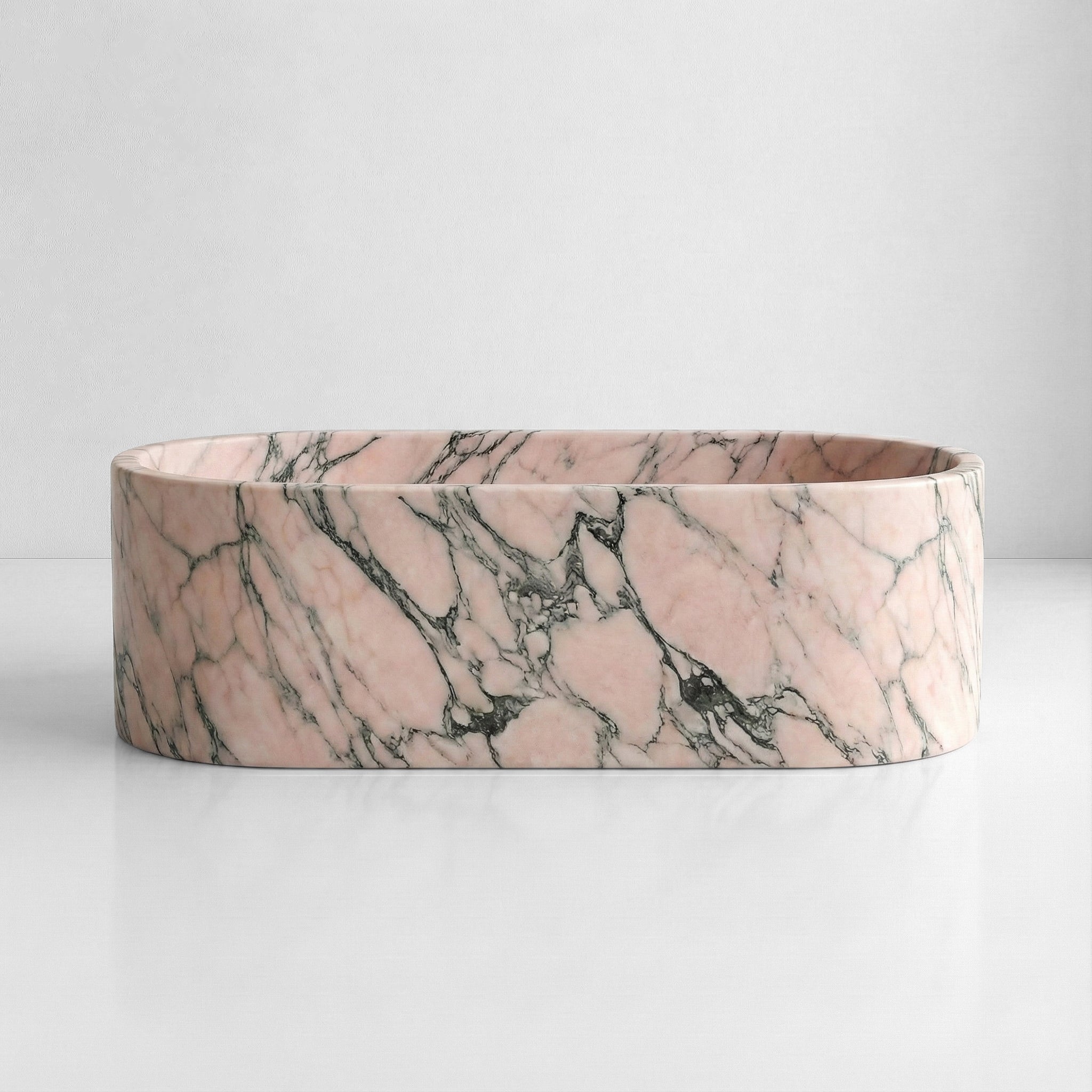 Front elevation of a solid oval bathtub carved from Rosso Portogallo marble, displaying a classic Estremoz pink and grey natural stone pattern.