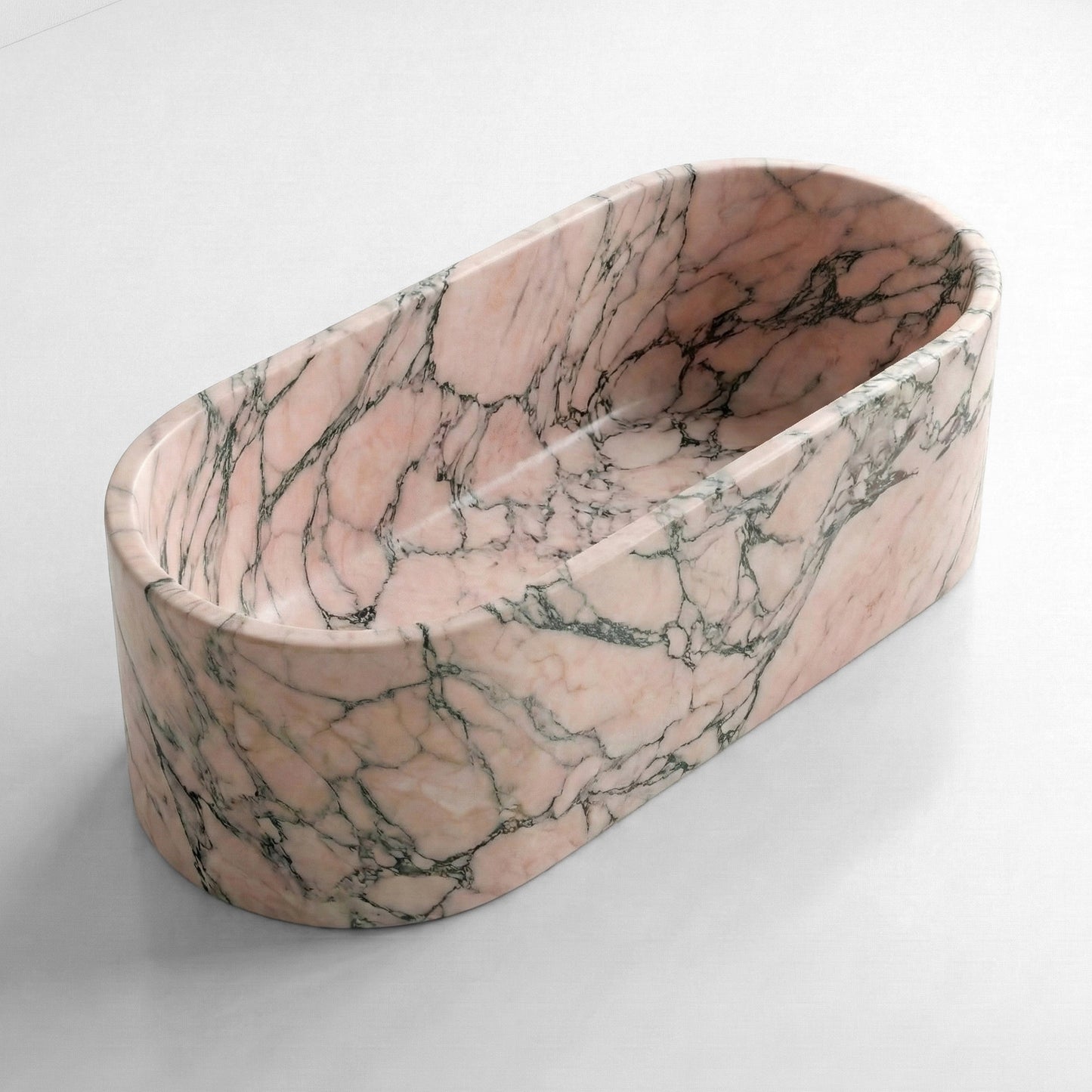Isometric side view of a freestanding Rosso Portogallo marble bathtub, showcasing the stone's soft pink hue and characteristic grey veining.