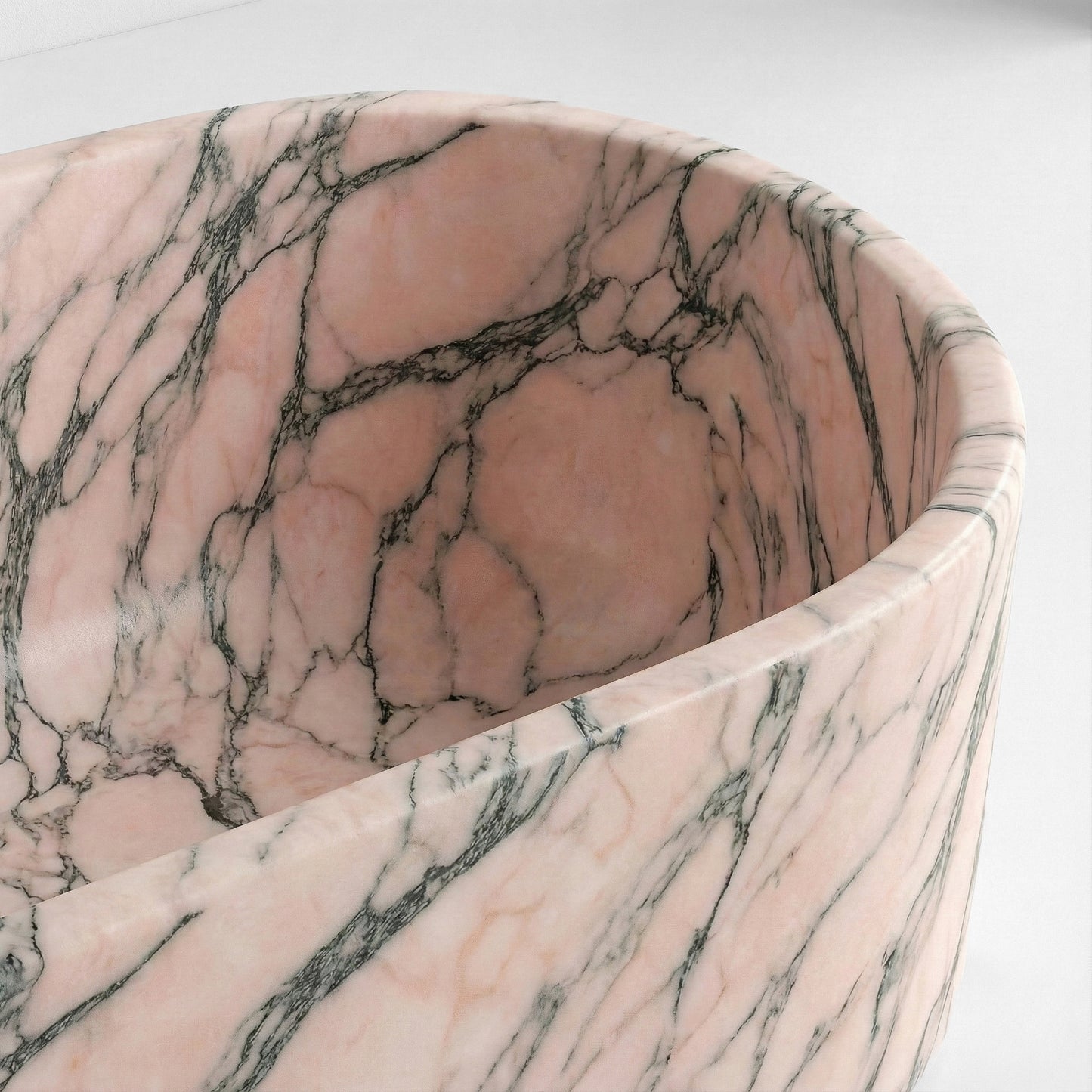 Close-up detail of a Rosso Portogallo bathtub rim showing the natural salmon-colored background and intricate mineral streaks.