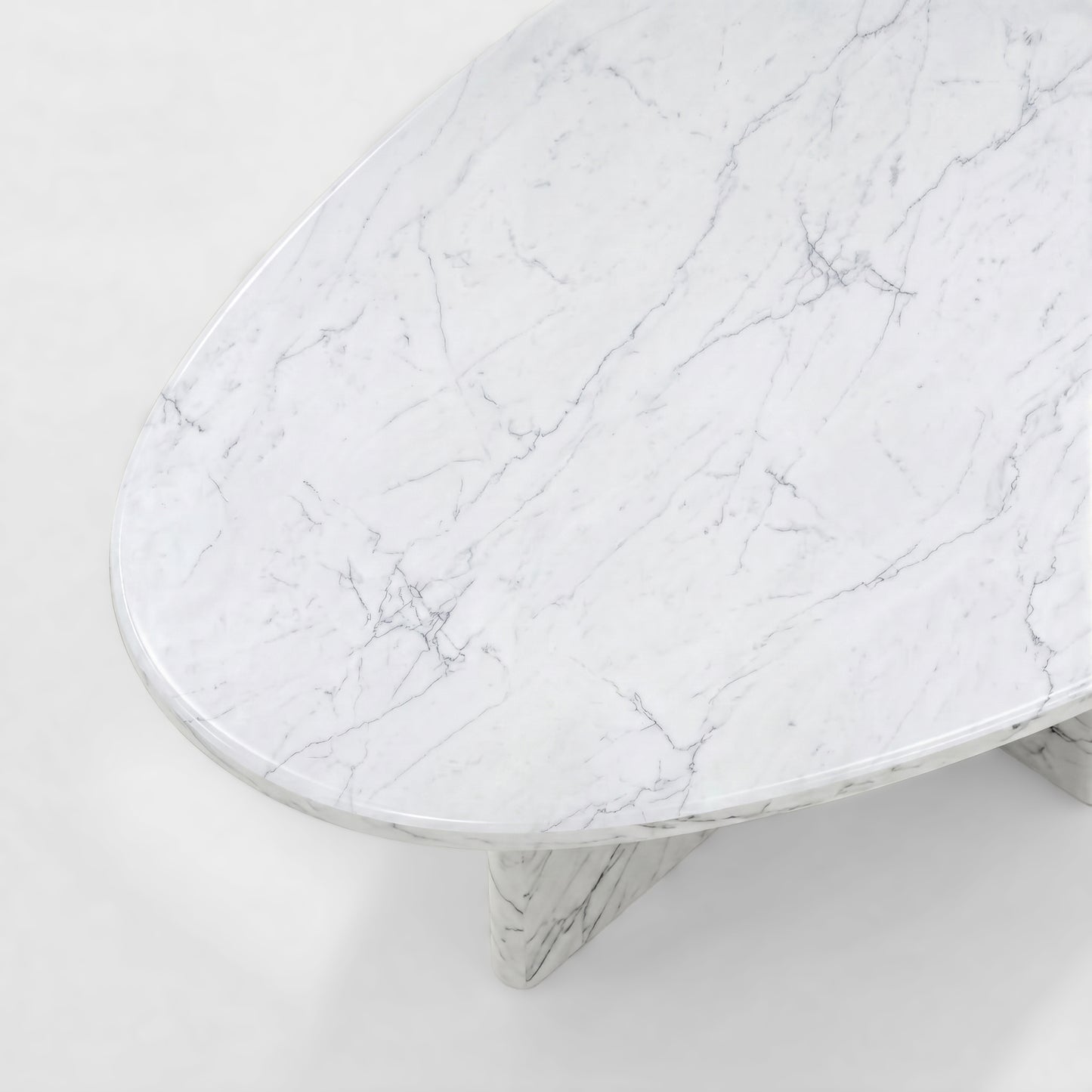 Side profile of a luxury White Carrara marble coffee table featuring a sculptural two-pedestal base and a thick pebble-shaped top against a minimalist white background.