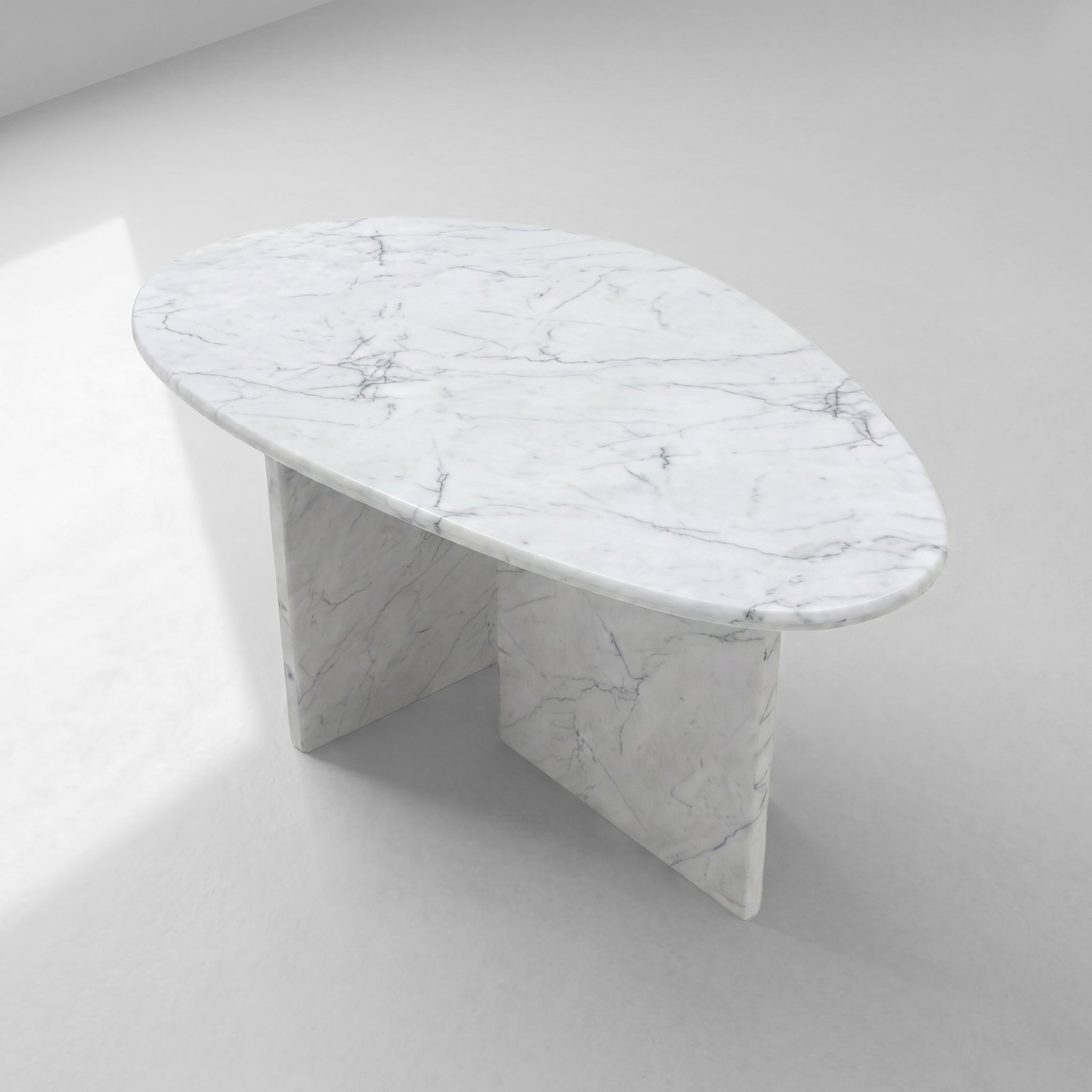 High-angle top view of a pebble-shaped White Carrara marble coffee table, highlighting its unique organic silhouette and classic natural stone patterns.